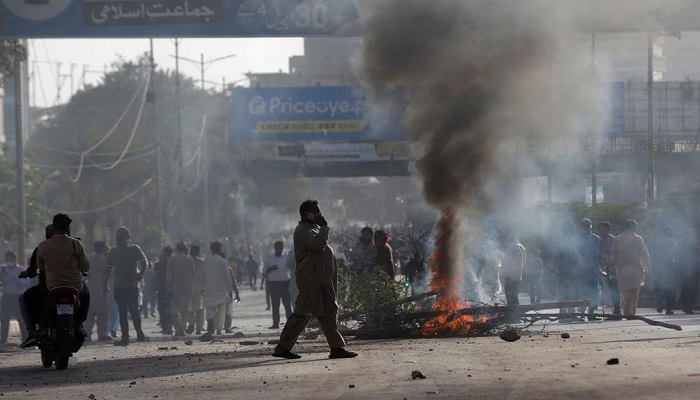 A man crosses a road past a barricade that was set afire by the supporters of Pakistans former prime minister Imran Khan during a protest against his arrest, in Karachi, May 9, 2023. — Reuters