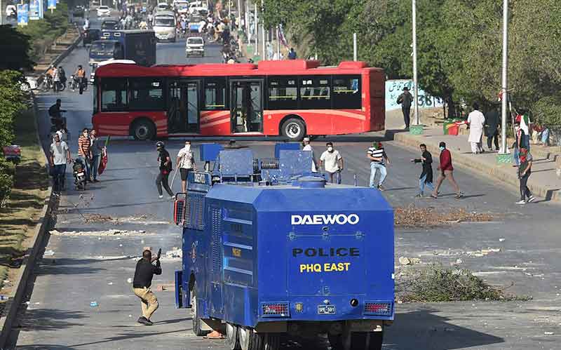 ایک پولیس (ایل) 9 مئی 2023 کو کراچی میں اپنے رہنما کی گرفتاری کے خلاف احتجاج کے دوران پاکستان تحریک انصاف (پی ٹی آئی) پارٹی کے کارکنوں اور پاکستان کے سابق وزیر اعظم عمران کے حامیوں کی طرف آنسو گیس کے شیل فائر کر رہی ہے۔
