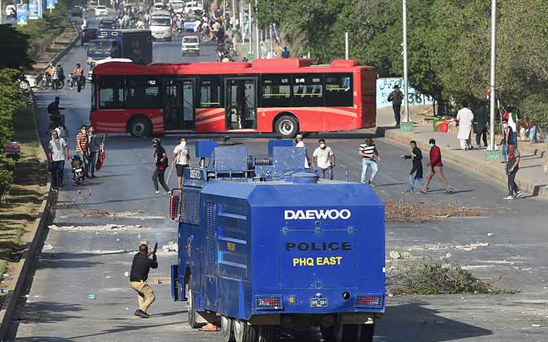 A police (L) fires a tear gas shells towards Pakistan Tehreek-e-Insaf (PTI) party activists and supporters of former Pakistan´s Prime Minister Imran during a protest against the arrest of their leader in Karachi on May 9, 2023.