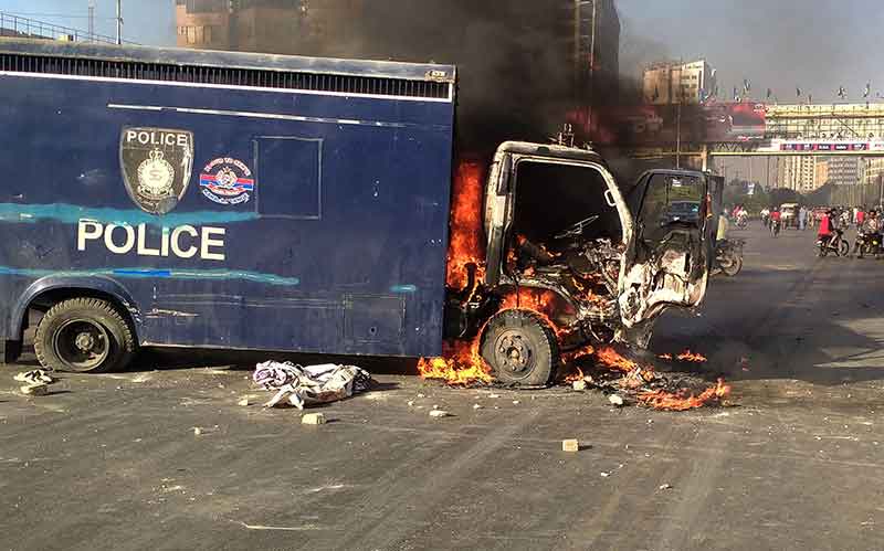 A police vehicle is seen burning along a road during a protest by Pakistan Tehreek-e-Insaf party activists and supporters of former Pakistan´s Prime Minister Imran against the arrest of their leader, in Karachi on May 9, 2023.