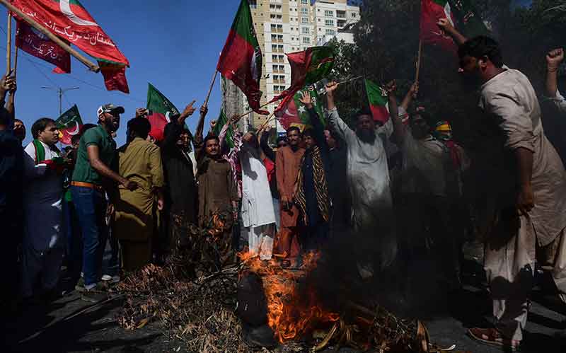 Pakistan Tehreek-e-Insaf party activists and supporters of former Pakistan´s Prime Minister Imran shout slogans next to a fire as they block a road during a protest against the arrest of their leader in Karachi on May 9, 2023.