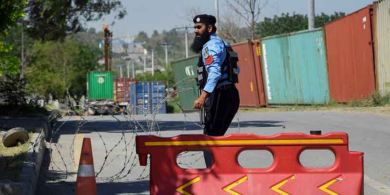 10 مئی 2023 کو اسلام آباد، پاکستان میں ایک پولیس افسر پولیس لائنز کے مرکزی دروازے کی طرف جانے والی سڑک کو روکنے کے لیے خاردار تاریں لگا رہا ہے، جہاں پاکستان کے سابق وزیر اعظم عمران خان کو گرفتاری کے بعد رکھا جا رہا ہے۔
