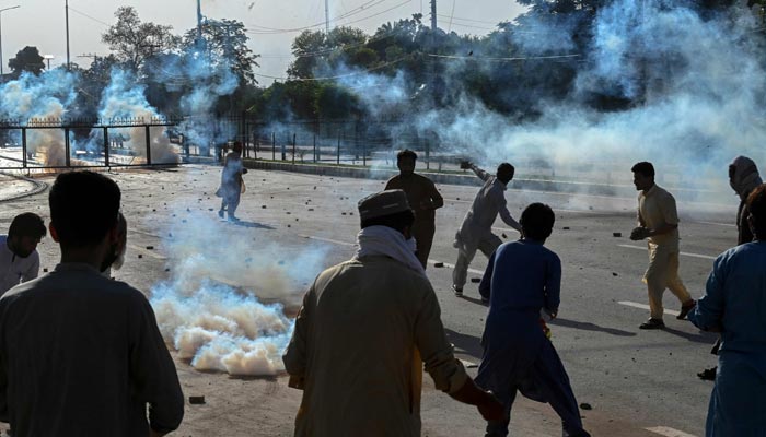 PTI party activists and supporters of former prime minister Imran Khan clash with police amid teargas during a protest against the arrest of their leader, in Peshawar on May 9, 2023. — AFP