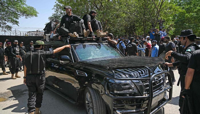 Security personnel escort a car carrying former prime minister Imran Khan as he arrives at the high court in Islamabad on May 9, 2023. — AFP