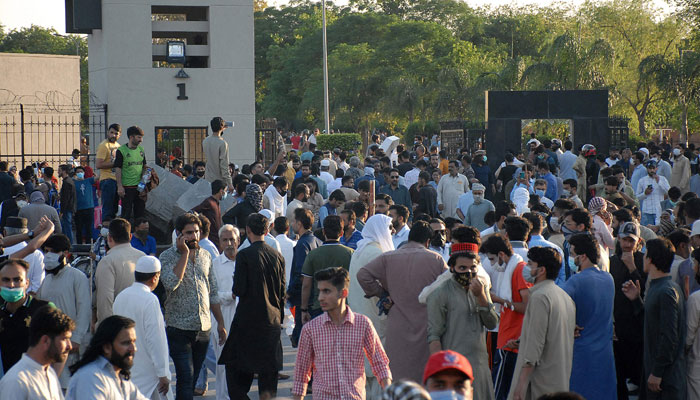 PTI activists and supporters of Imran Khan gather in front of the main entrance of General Headquarters during a protest against the arrest of their leader, in Rawalpindi on May 9, 2023. — AFP