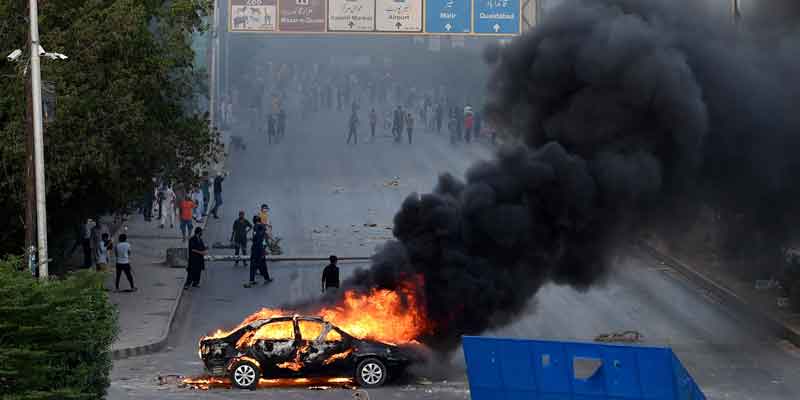 A car is seen burning along a road as Pakistan Tehreek-e-Insaf (PTI) party activists and supporters of former prime minister Imran Khan block a road during a protest against the arrest of their leader in Karachi on May 9, 2023. — AFP