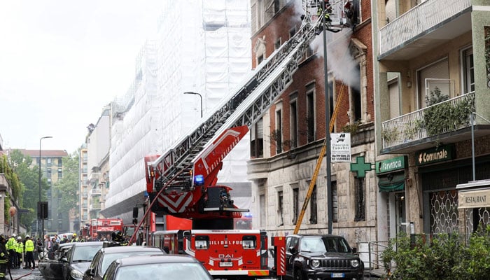 Firefighters spray water at a house on fire following an explosion in the centre of Milan, Italy, May 11, 2023. — Reuters