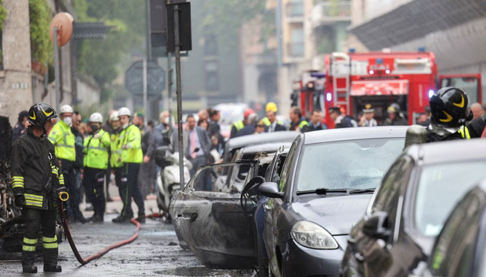 A firefighter stands next to a burnt vehicle following an explosion in the centre of Milan, Italy, May 11, 2023. — Reuters