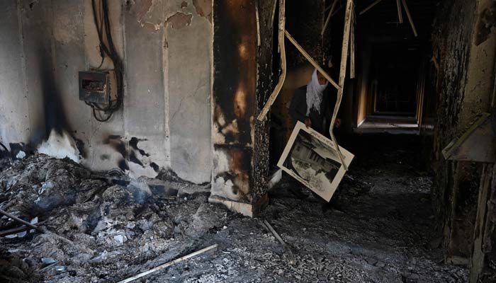 A man walks inside the burnt Radio Pakistan building a day after protests by PTI activists and supporters in Peshawar on May 11, 2023. — AFP