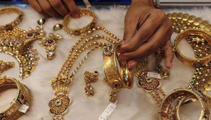 A salesperson displays gold jewellery at a store in this undated file photo. — Reuters