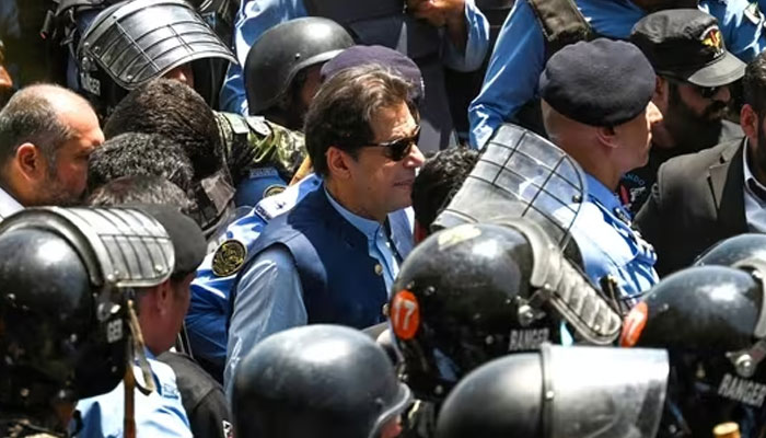 Policemen escort Pakistans former Prime Minister Imran Khan (C) as he arrives at the high court in Islamabad on Friday. AFP/