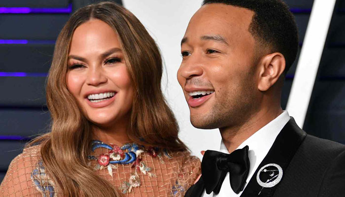 People surrounded the smiling family as Teigen performed the ribbon-cutting ceremony for her bakery