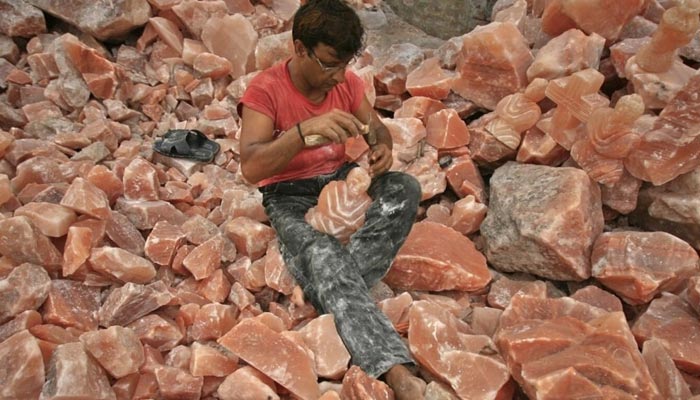 A man applies the final touches to a sculpture made from Himalayan pink rock salt on the outskirts of Lahore. — Reuters