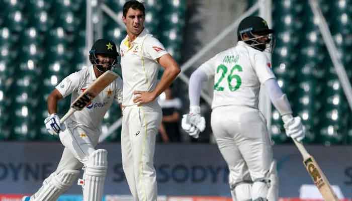 Pakistani cricketers take runs while Australias former Test skipper Pat Cummins watches during a Test match. — AFP/File