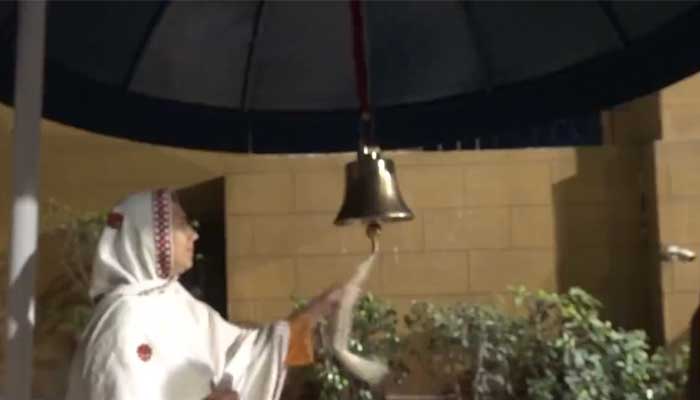 A woman rings a bell of hope installed outside Gate No. 1 of the Governor's Mansion in Karachi in this image from a video — Twitter/@psec_governor