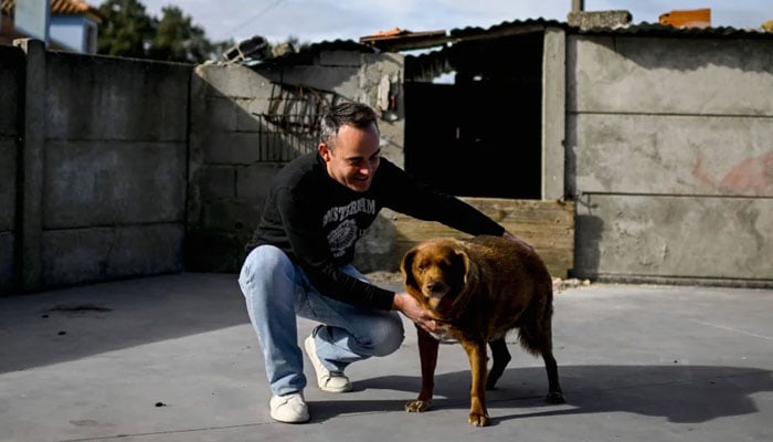 Leonel Costa caresses Bobi at their home in the village of Conqueiros near Leiria. —AFP