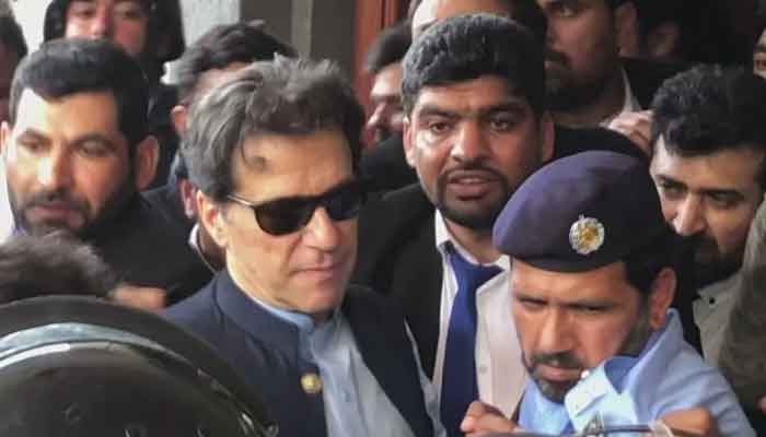 PTI Chairman Imran Khan seen surrounded by a crowd of security personnel and his lawyers people as he leaves Islamabad High Court (IHC) on May 12, 2023. — AFP