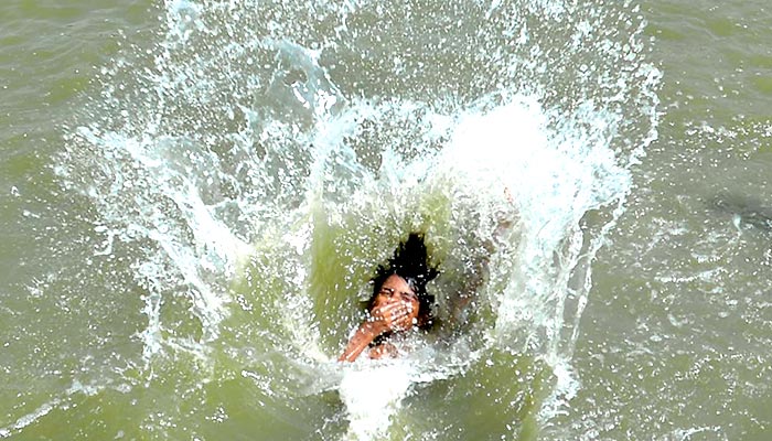 A boy dives into a water pond as hot weather hits Hyderabad, on May 15, 2023. — INP