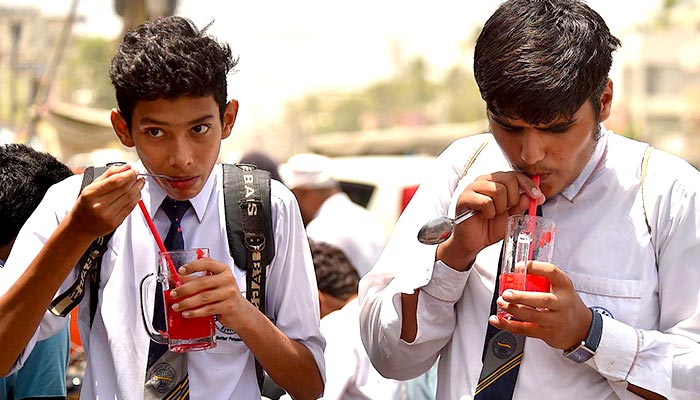 School students drink watermelon juice amid hot weather in Karachi, on May 15, 2023. — INP