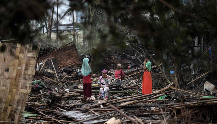 Rohingya women sit and stand in their destroyed house at Basara refugee camp in Sittwe on May 16, 2023, after cyclone Mocha made landfall. — AFP