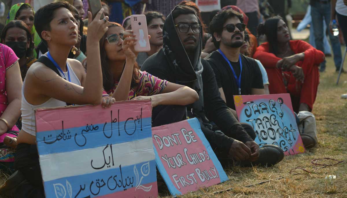 Activists and supporters of the trans community seated with placards at the Moorat march in Karachi on November 20, 2022. — AFP