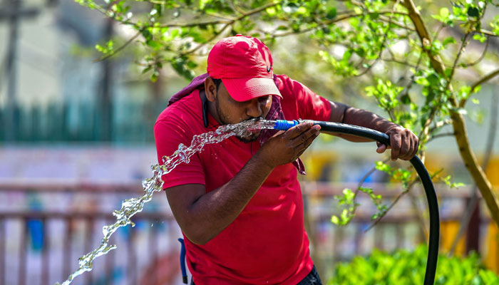 This photo shows a man drinking from a running water pipe on a hot summer afternoon in Prayagraj. — AFP/File