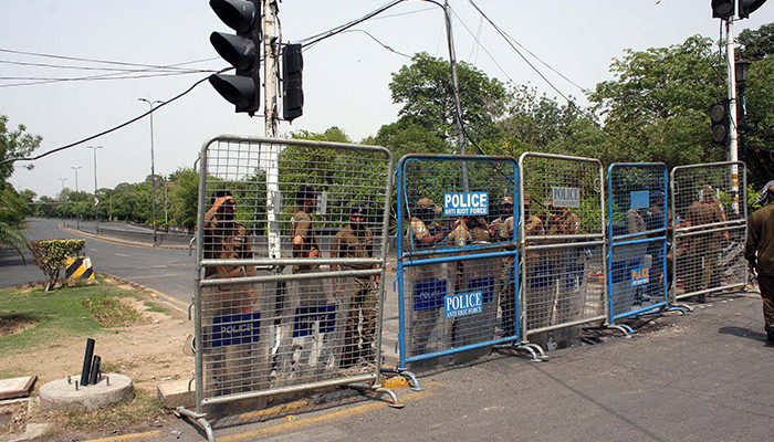پولیس اہلکار 18 مئی 2023 کو لاہور میں زمان پارک جانے والی سڑک کو بند کر رہے ہیں۔ — PPI