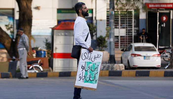 A supporter of PTI Chairman Imran Khan, holds a placard as he along with others gather for what they call a true freedom protest, demanding Save constitution - Save Pakistan, in Islamabad, Pakistan, May 14, 2023. — Reuters