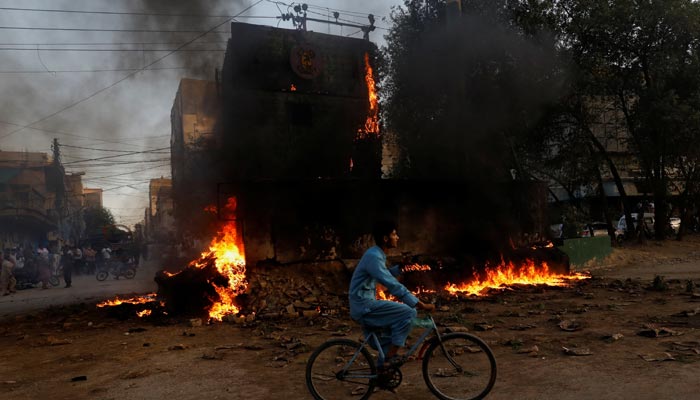 A boy rides past a paramilitary check post, that was set afire by the supporters of former prime minister Imran Khan, during a protest against his arrest, in Karachi, Pakistan, May 9. — Reuters