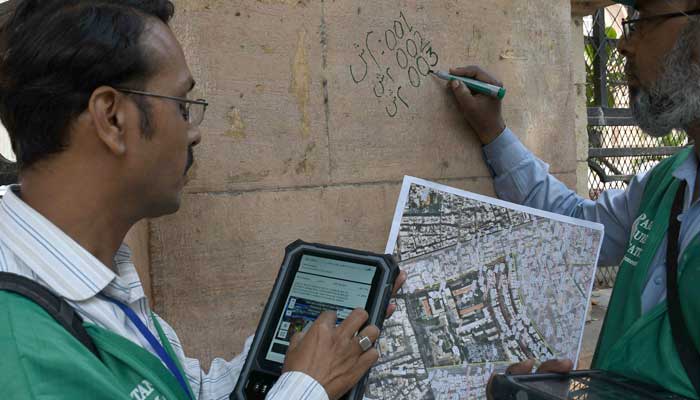 An official from the Pakistan Bureau of Statistics marks a house after collecting information from a resident during population census in Karachi on March 1, 2023. — Online