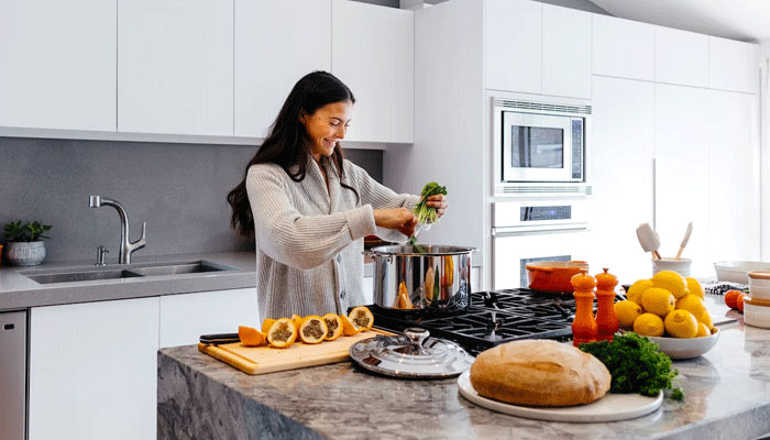 A representational image of a woman cooking food with fresh vegetables. — Unsplash/File