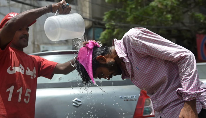An Edhi volunteer pours water on a pedestrian along a street during a hot summer day in Karachi on May 16. — AFP/File