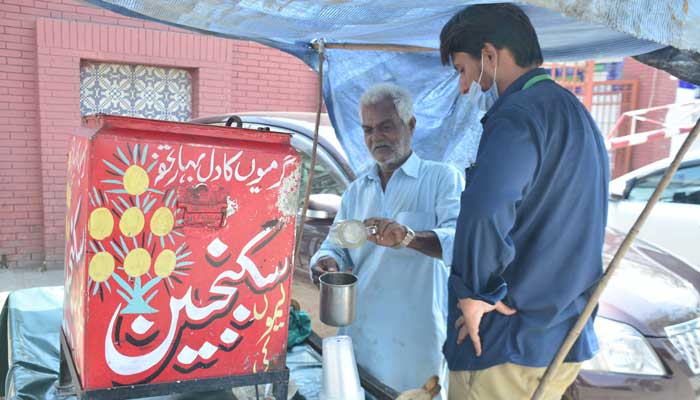 A man pours lemon juice for a customer during hot weather in Rawalpindi on May 18, 2023. — Online
