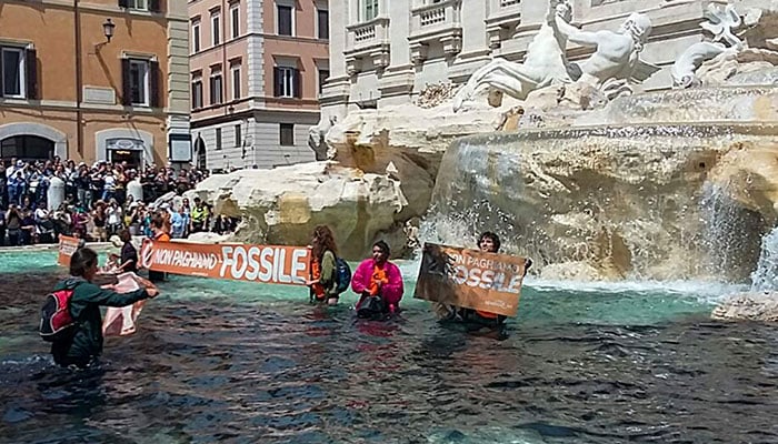 A photo taken and issued as a handout on May 21, 2023, by environmental activists of Last Generation (Ultima Generazione) shows the group´s activist holding a banner reading We don´t pay for the fossil in Rome´s historic Fontana di Trevi fountain after the activists poured black liquid made out of vegetable-based carbon into the water as part of a campaign to raise awareness about climate change.—AFP