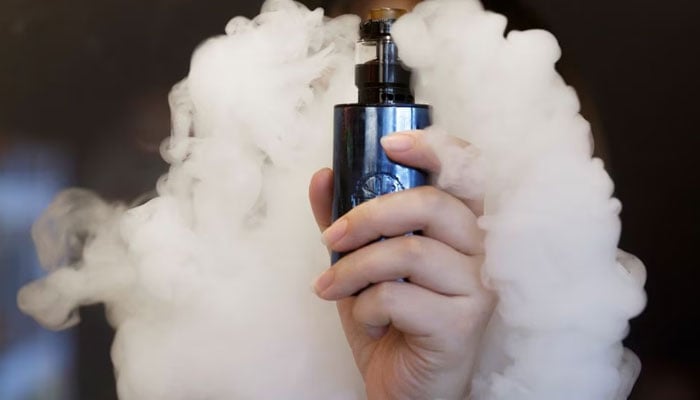 A saleswoman holds an e-cigarette as she demonstrates vaping at the Vape Shop that sells e-cigarette products in Beijing, China. — Reuters/File