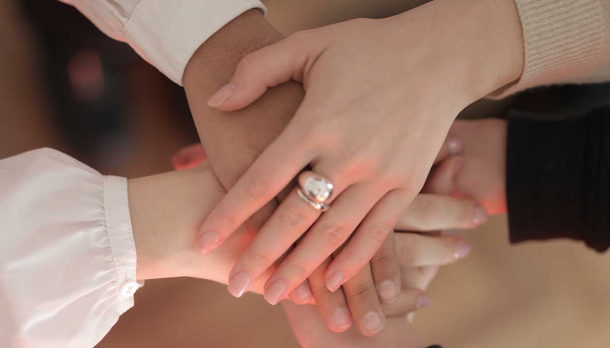 A representational image of women placing their hands on those of one another as a show of support. — Pexels