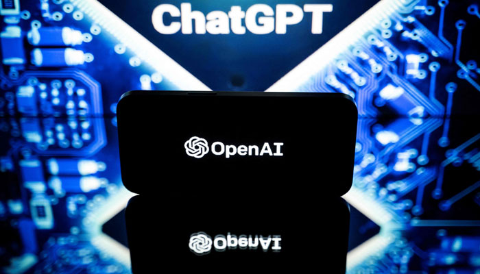 A screen can be seen showing the OpenAI logo with ChatGPT visible behind the phone. — AFP/File
