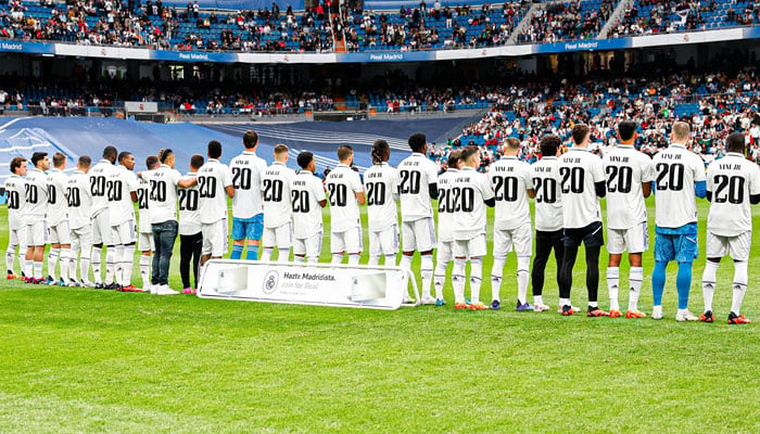 Real Madrid players standing wearing Vinícius Jr.s No. 20 shirt. Twitter/realmadriden