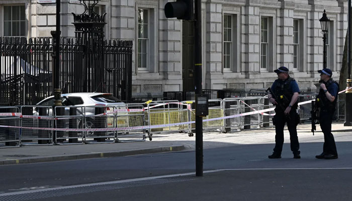 Police officers stand near the car that was driven into the gates of 10 Downing Street. — AFP