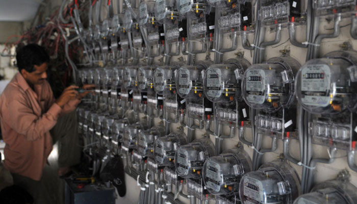 A technician from K-Electric fixes new electricity meters at a residential building in Karachi. — AFP/File