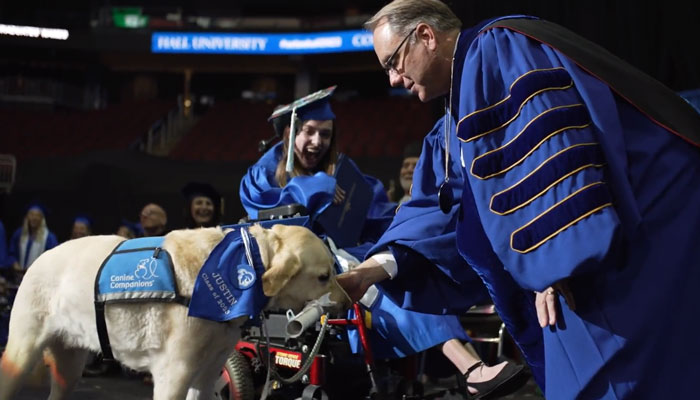 Seton Halls Joseph E. Nyre presents an honorary diploma to a students service dog named Justin during a graduation ceremony at the varsity in this still taken from a video. — Twitter/@SetonHall