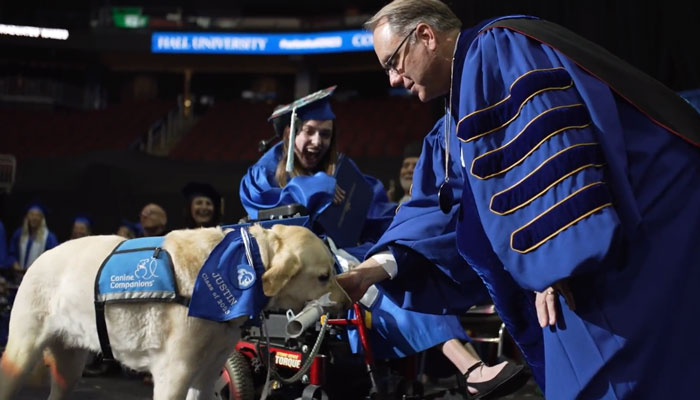 Seton Halls Joseph E. Nyre presents an honorary diploma to a students service dog named Justin during a graduation ceremony at the varsity in this still taken from a video. — Twitter/SetonHall