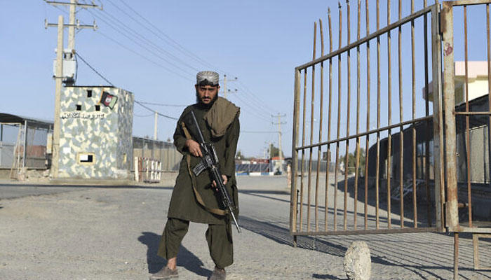 A Taliban fighter stands guard at the entrance gate of Afghan-Iran border crossing bridge in Zaranj, February 18, 2022. — AFP