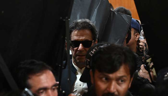 Security personnel with ballistic shields escort PTI Chairman Imran Khan as he leaves after appearing at the high court in Lahore on May 19, 2023. — AFP