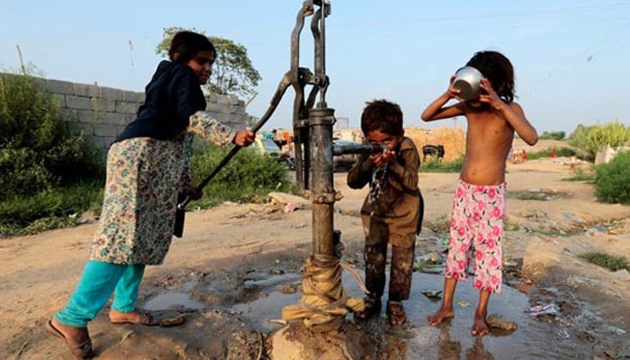 An undated image of children drinking water from a hand pump in a slum in Islamabad. — Reuters