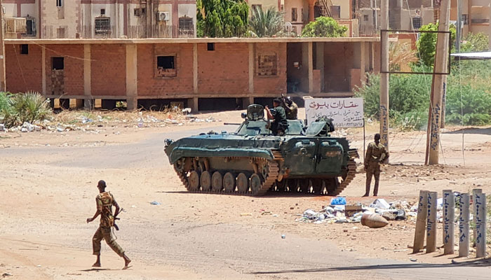 Sudanese Army soldiers walk near tanks stationed on a street in Khartoum, on May 6, 2023. — AFP