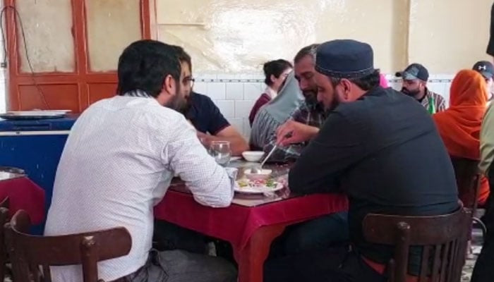 تصویر میں کراچی میں ایک ایرانی کیفے کے اندر گاہک بات کرتے اور کھاتے ہوئے دکھائی دے رہے ہیں۔  - مصنف