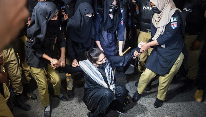 Police officers detain a PTI party activist and supporter of former Prime Minister Imran Khan during a protest against the arrest of their leader in Karachi on May 10, 2023. - AFP