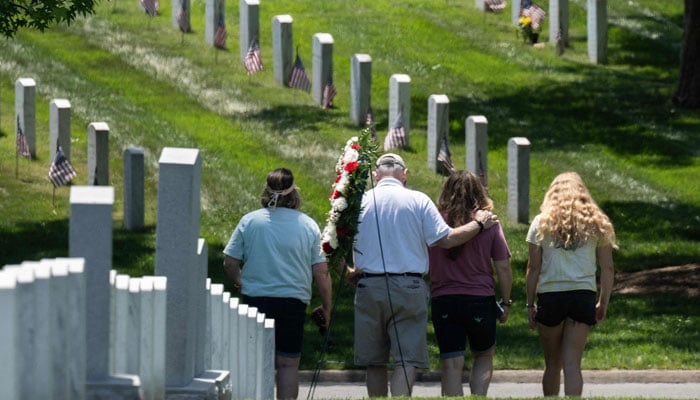 A family walks through section 60 after visiting a headstone at Arlington National Cemetery before the Memorial Day weekend in Arlington, Virginia on May 26, 2023. — AFP