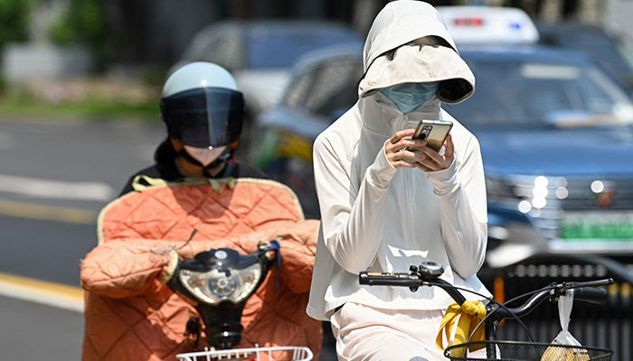 A woman wearing sun-protective clothing commutes on a bicycle amid hot weather in Shanghai on May 29, 2023. Shanghai on May 29 recorded its hottest May day in 100 years, the city´s meteorological service announced, shattering the previous high by a full degree.—AFP